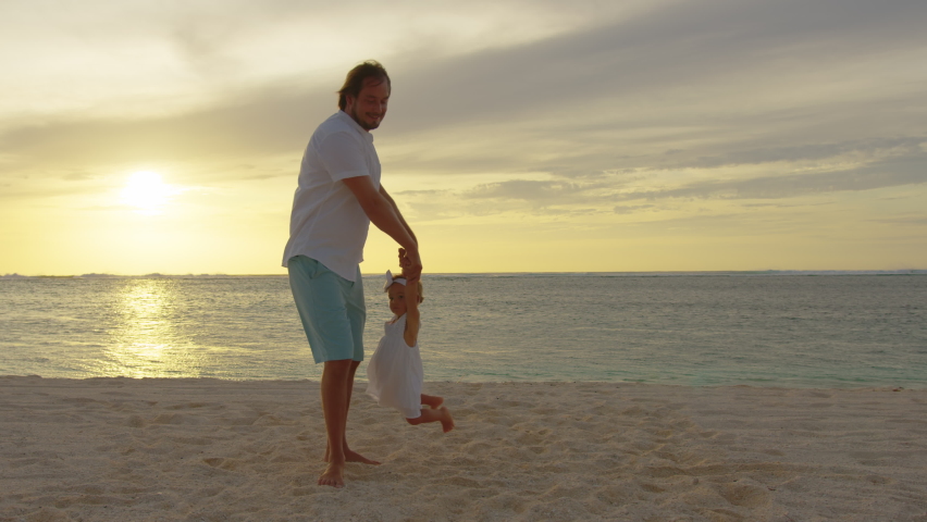 Dad and daughter play on the beach. Kid dream concept happy family playing. Dad and daughter lifts her into fun the air. happy family on the seaside. Family, freedom and travel concept
