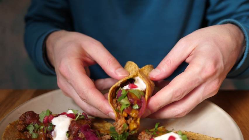 Portrait man eating tasty juicy tacos in Mexican cuisine restaurant
