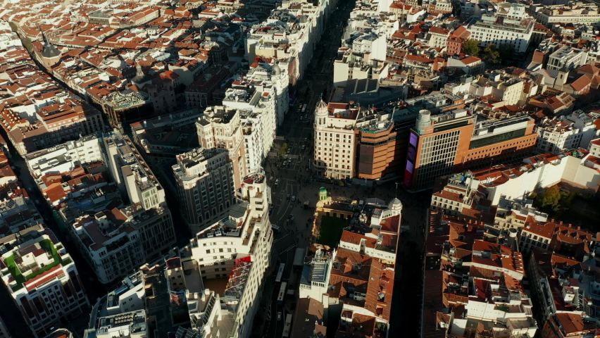 Forwards fly above Gran Via famous shopping street in city centre. Tilt up reveal cityscape. Royalty-Free Stock Footage #1086786923