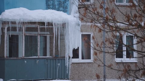 Nizhny Novgorod, January 27, 2022.  An elderly woman looks at icicles from the window of her apartment