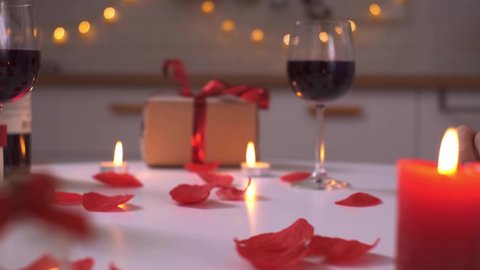 Hands of a couple in love put together the word love. The word love is laid out from cubes. A pair of lovers sits at a table celebrate Valentine's Day. Romantic candles furnishings wine
