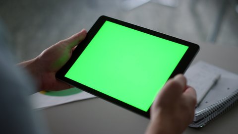 Businessman swiping digital tablet device green screen analyzing corporate information in home office. Close up male hands using tab computer in cafe. Unknown manager browsing web. Technology concept.