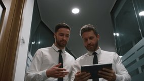Two managers discuss financial business data using digital tablet in office centre. Couple businessman walking together talking corporate plan in workplace corridor. Teamwork communication concept. - Powered by Shutterstock - Get 15% off with code: PIKWIZARD15