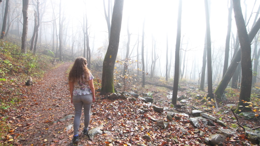 Young woman hiking on Upper Shamokin falls forest woods trail in Wintergreen Resort, Virginia in morning foggy misty weather at sunrise on rocky footpath in Blue Ridge Mountains