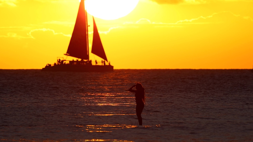 A girl surfer staying on surf board waiting for waves at perfect sunset time in slow motion in the background