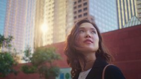Closeup cute woman looking back on high building going city street. Portrait of attractive asian girl on sunlight. Beautiful girl face watching up on cityscape. Pretty lady walking alone on megapolis. - Powered by Shutterstock - Get 15% off with code: PIKWIZARD15