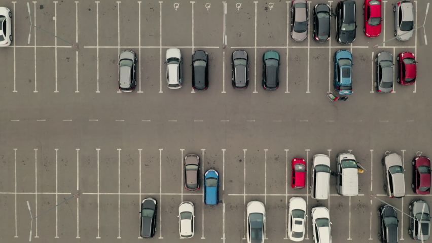 Blue car pulls out of the parking lot. Car leaves the parking lot - an aerial top overhead view. Parking with many places near the supermarket - overhead view. | Shutterstock HD Video #1086799145