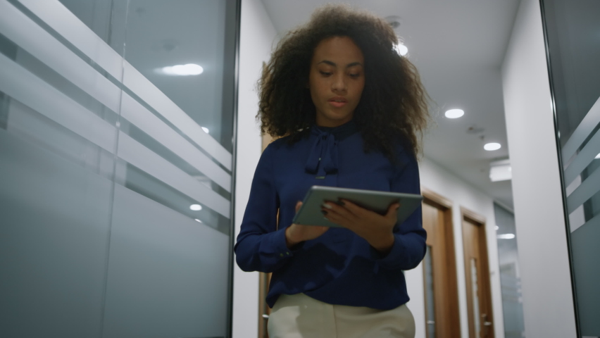 African american businesswoman working on go in office. Business woman ceo using tablet computer browsing internet in hallway. Focused manager walking corridor. Corporate professional busy concept.  Royalty-Free Stock Footage #1086799235