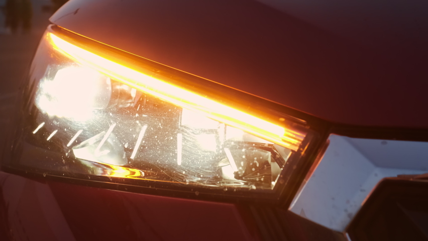 A fast blinking turn signal or blinker of a red car in the evening.