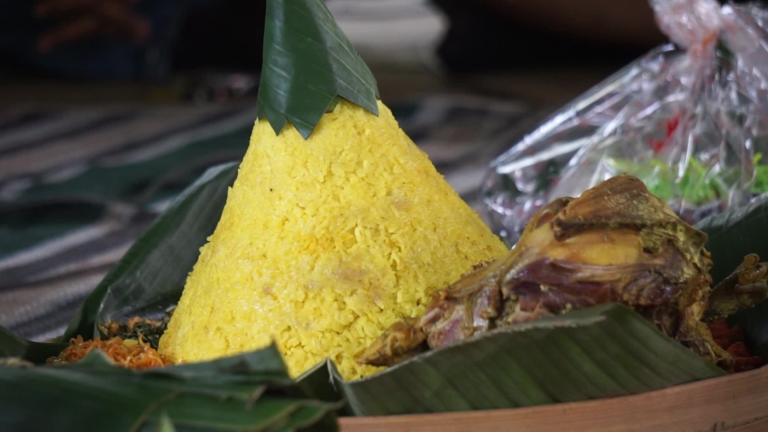 Indonesian thanksgiving menu that called nasi tumpeng (rice with cone shape). Nasi tumpeng usually eat at birthday party, graduation or thanksgiving Royalty-Free Stock Footage #1086799922