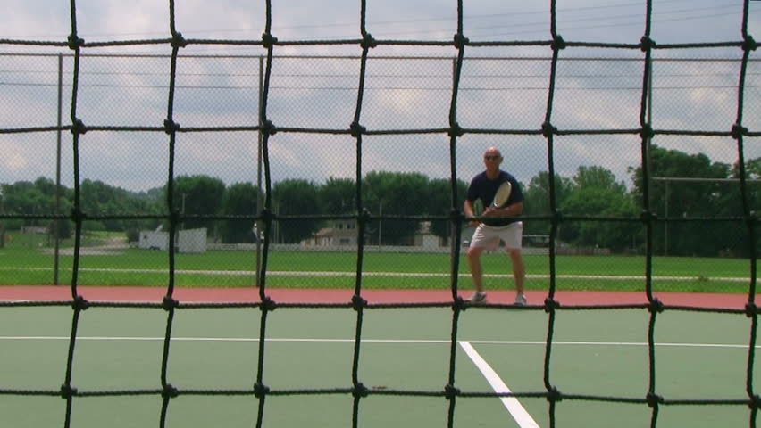 Tennis player volleys using forehand technique, crane shot from net.