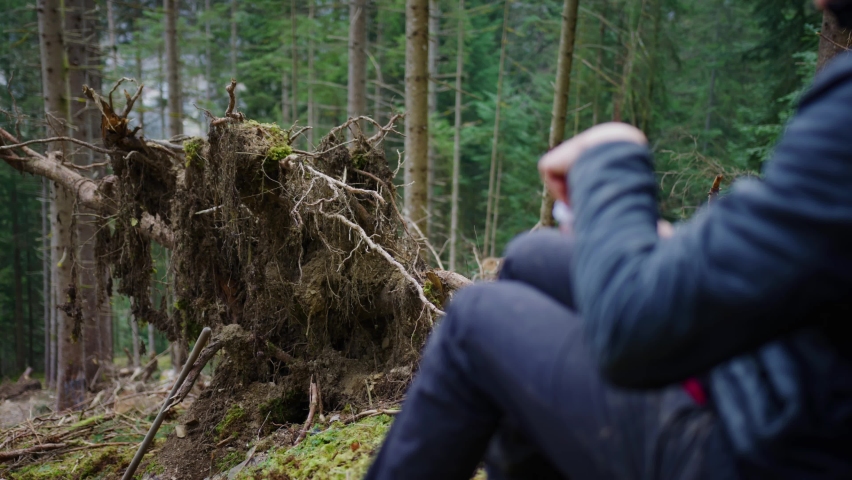 A man is eating a snack sat down in the forest alone