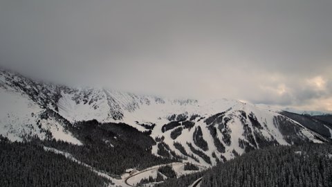 Loveland Pass Colorado USA. Drone Aerial Footage Of Snow Covered Rocky Mountains Alpine Peaks And Slopes with Low Clouds.