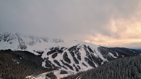 Loveland Pass Colorado USA. Drone Aerial Footage Flying Over Snow Covered Rocky Mountains Alpine Trees And Slopes During Beautiful Golden Hour Sunset.