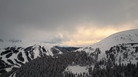 Loveland Pass Colorado USA. Drone Aerial Footage Of Beautiful Golden Hour Sunset Over Snow Covered Rocky Mountains Alpine Peaks And Slopes.