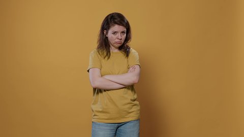 Seriously upset woman with arms crossed feeling sad and disappointed looking grumpy mumbling in studio. Bored young person feeling annoyed and stressed because of personal problems.