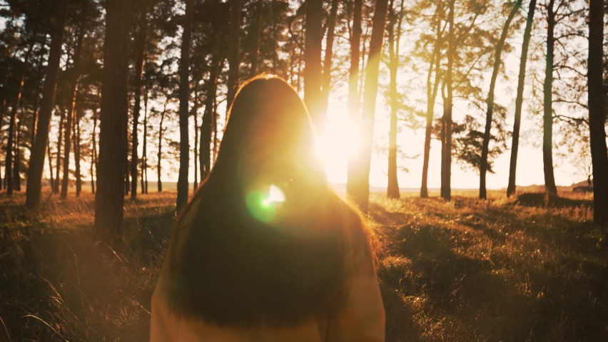 Girl walks through natural forest. Woman hiking alone. Teenager girl in nature at sunset. Fantasy of people in park in autumn. Active lifestyle. People in forest. Tourist walk in autumn forest park