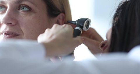 ENT doctor conducts medical examination of ear with otoscope closeup