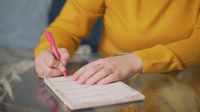 Woman is writing something on sheets of paper at glass table with pen. She reads something and corrects it with pen. Studying something, preparing for speech, checking contract, training, lecture
