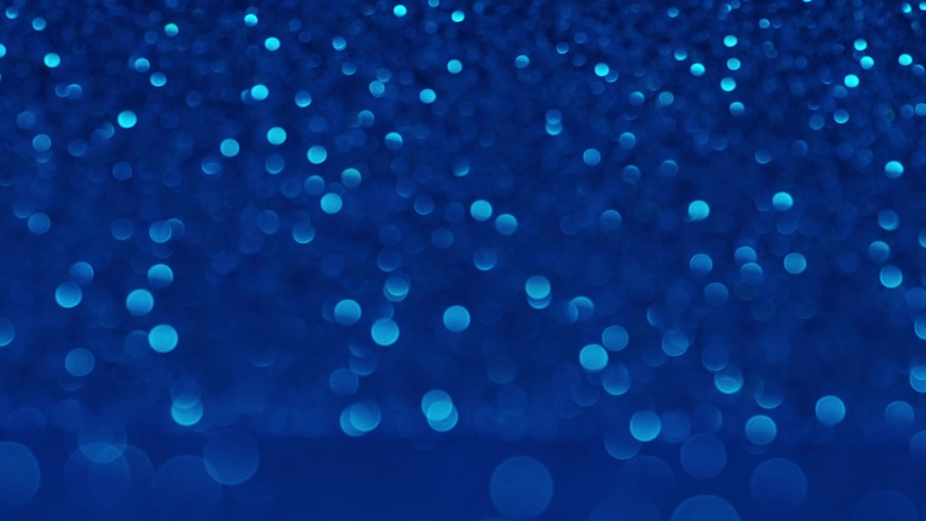 Moving blue glitter lights, defocused light reflections loopable bokeh background. Defocused Particles Background. Beautiful blue glowing bokeh, shallow depth of field, abstract background
