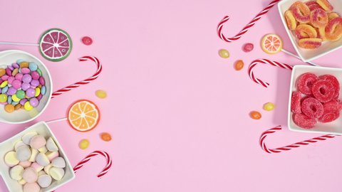 6k Sweet colorful candies and lollypops appear on left and right side of bright pink background, Stop motion animation flat lay
