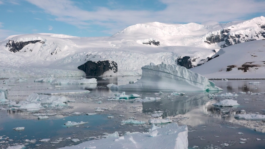 Icebergs. Moving Ice Floes and Ice Sheets in the calm Antarctic Sea, Reflection of Antarctica Mountain in water surface. Amazing beautiful views of Nature and landscape of snow and  ice.  