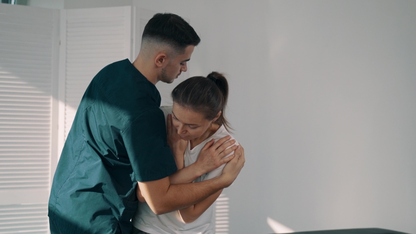 Professional male chiropractor, physiotherapist treating female patient in rehabilitation center