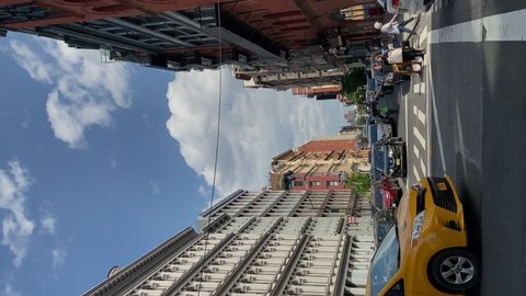 NEW YORK, USA - MAY, 18, 2021: Vertical video. Manhattan Soho district buildings and streets. Old historic buildings in midtown, a house with fire escapes. Cars and bus at the crossroads.