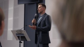 Speech of male employee at business conference for office workers. Speaker talks to audience at scene in crowded hall. Adult man explains motivation to group of people. Summit meeting at modern event - Powered by Shutterstock - Get 15% off with code: PIKWIZARD15