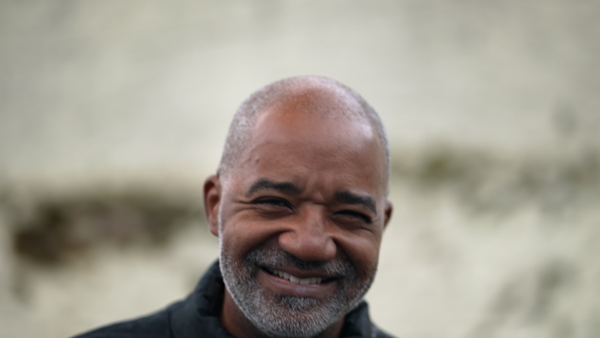 A happy senior black man portrait face smiling at camera standing outside in street