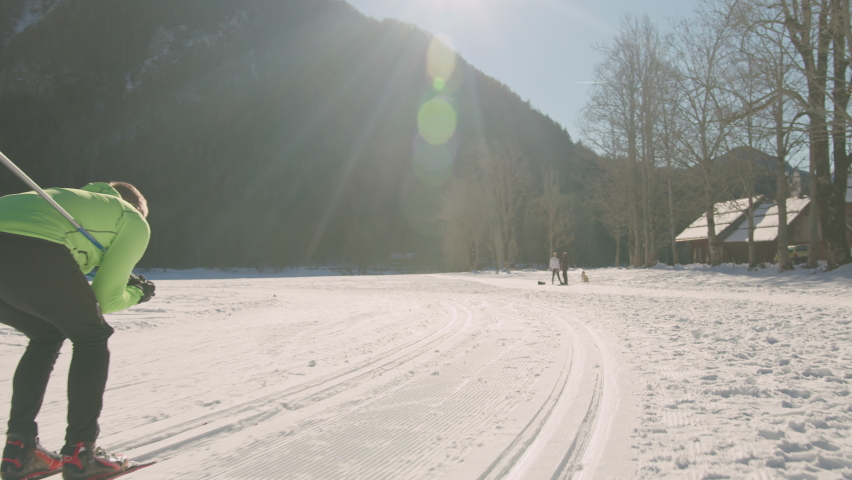 Man performing cross country downhill skiing technique, in the squat position and folded the upper body, the ski poles are trapped under the arms, tracking shot. Royalty-Free Stock Footage #1086830837