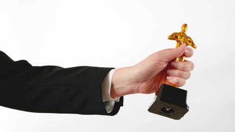 Hollywood Golden Oscar Academy award statue in hand on white background. Success and victory concept.