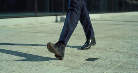 Cinematic close up shot of legs with black leather shoes of anonymous business man is walking in busy city center street on way to office before to start his work day. 