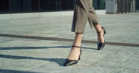 Cinematic close up shot of legs with black leather shoes of anonymous business woman is walking in busy city center street on way to office before to start her work day. 