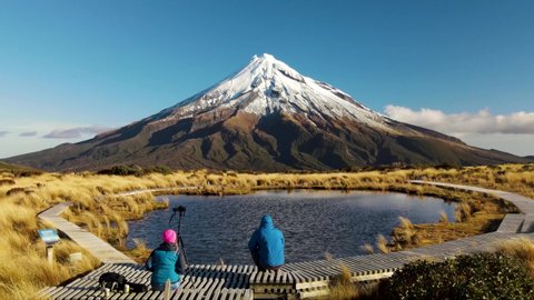 Outstanding scene at Taranaki volcano, New Zealand. Tourists waiting for reflection in Tarn to take photos at famous hiking spot.