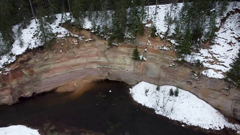 Aerial view of sand cliff outcrop next to a river at winter