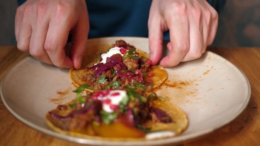 Portrait man eating tasty juicy tacos in Mexican cuisine restaurant