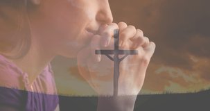 Animation of caucasian woman praying and crucifix at sunset. national day of prayer, religion and tradition concept digitally generated video.