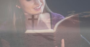Animation of caucasian woman reading holy bible and crucifix at sunset. national day of prayer, religion and tradition concept digitally generated video.