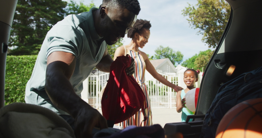 Happy african american family packing car with beach balls on holiday. family spending time together outdoors. Royalty-Free Stock Footage #1086848888