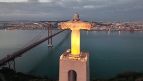 Drone flight around the statue of Jesus Christ in Lisbon. Jesus monument in sunset light. The god statue over the night landscape. Jesus protecting Portugal people.