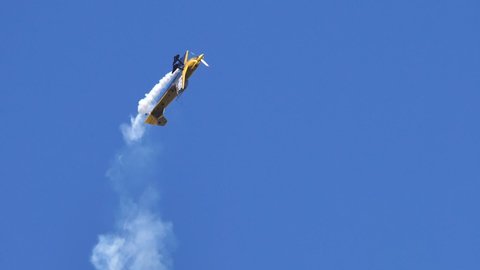 Vicenza Italy OCTOBER, 16, 2021 Small yellow aeroplane flips horizontally performs aerobatics in the sky releasing smoke. Amazing aerobatics acrobats. Extreme sports. Slow-motion. Mudry CAP 231