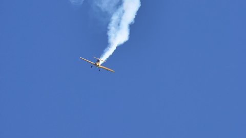 Thiene Vicenza Italy OCTOBER, 16, 2021 Amazing aerobatics acrobats performance of a small aircraft in the clear sky. Releasing white aerobatics smoke. Extreme sports. Slow-motion footage. Mudry CAP231