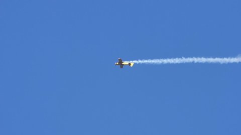 Vicenza Italy OCTOBER, 16, 2021 Airplane performs tricky aerobatics maneuvers in the clear blue sky. A line of white smoke behind the vehicle. Extreme sports in slow-motion. Mudry CAP 231