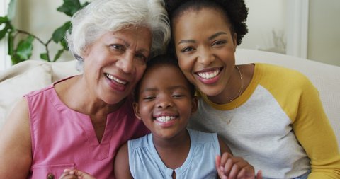 Portrait of happy african american grandmother with adult daughter and granddaughter. family spending time together at home.