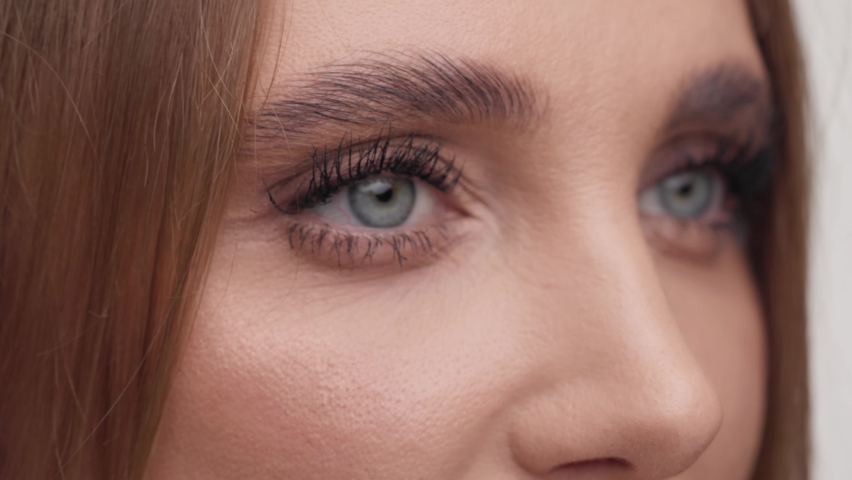 Close up of female face. Attractive woman opening her beautiful green eyes with long eyelashes and thick eyebrows. Highly detailed portrait of human face. Skin care concept. Royalty-Free Stock Footage #1086851588