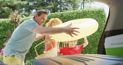 Happy caucasian couple with son packing car and preparing for holiday. family spending time together outdoors.