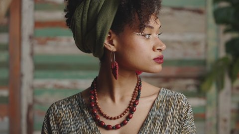 Ethno beauty. Close up portrait of young confident gorgeous stylish african american woman with traditional accessories turning face to camera, slow motion