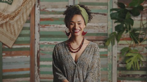 Young stylish african american woman wearing ethno style smiling to camera, posing over rustic background