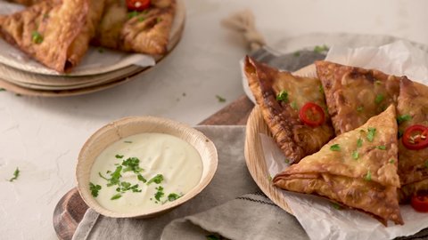 Indian samosas  - fried or baked pastry with savoury filling, popular Indian snacks, served in areca leaf dishes with spices on kitchen countertop.
